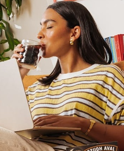 A woman enjoying a coffee at her laptop